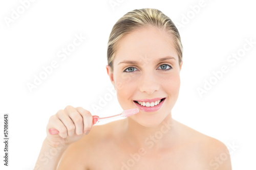 Amused fresh blonde woman brushing her teeth
