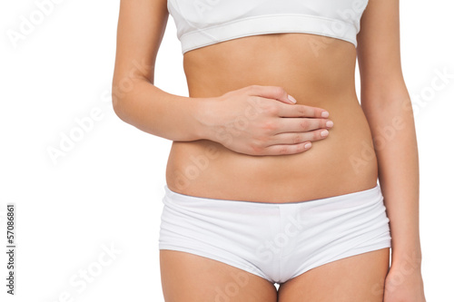 Mid section of slim woman touching her belly with one hand