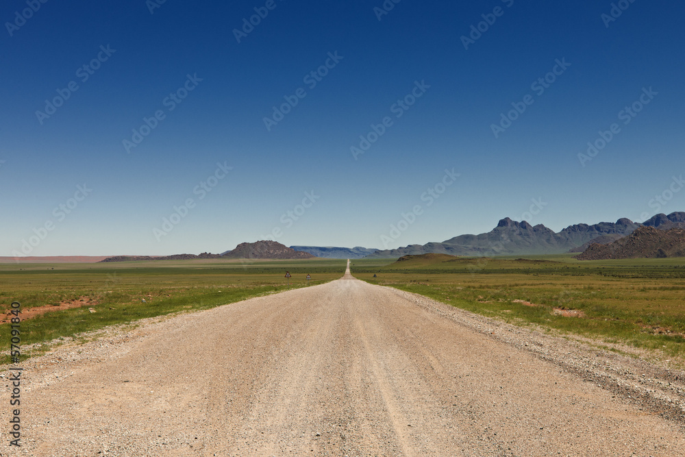 endlos gerade Schotterstraße in einer Wuestenlandschaft, Namibia