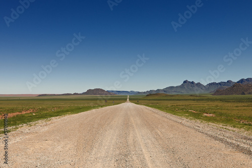 endlos gerade Schotterstraße in einer Wuestenlandschaft, Namibia