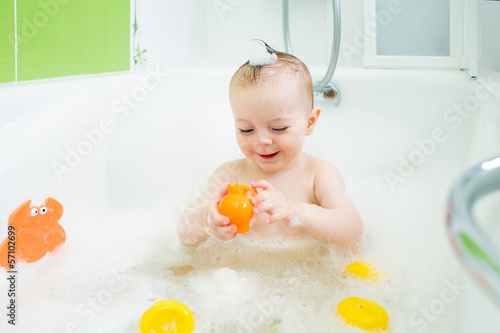 smiling baby girl taking bath and playing with toys