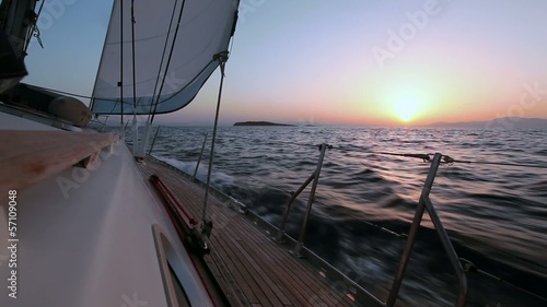 Sailing boat in the wind through the waves during sunset