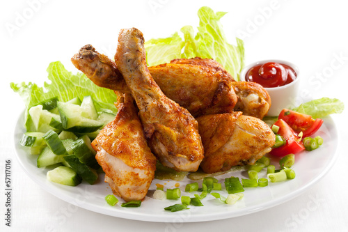 Grilled chicken legs and vegetables on white background