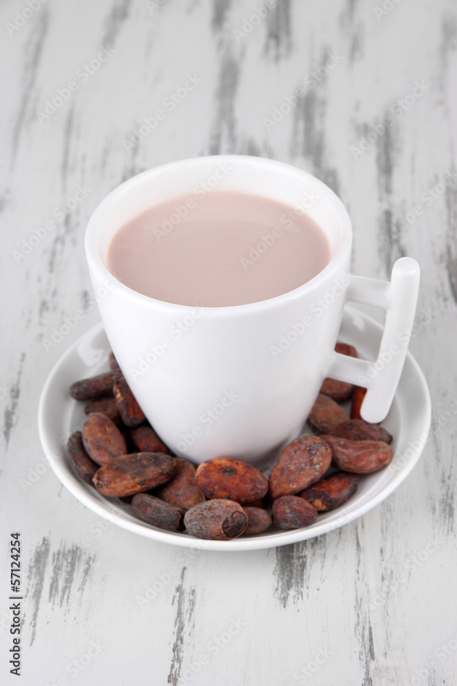 Cocoa drink and cocoa beans on wooden background