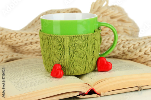 Cup with knitted thing on it and open book close up