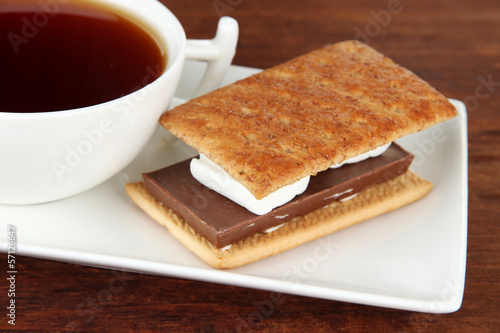 Sweet sandwich with cup of tea on wooden background