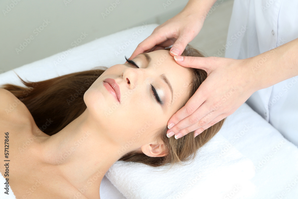 Beautiful young woman during facial massage in cosmetic salon