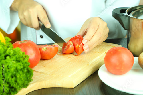 Cook hands cutting tomato