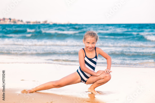 Beautiful little girl excercising on the beach © len44ik