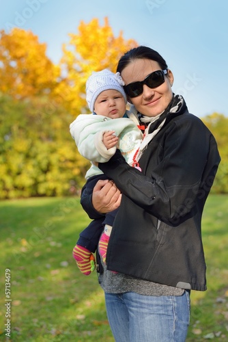 Mother with her baby in autumn scenery.