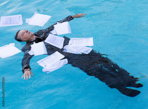 Fotografía Senior man floating among papers in water