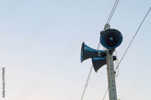 Three speakers are installed on a concreat pole wires against.