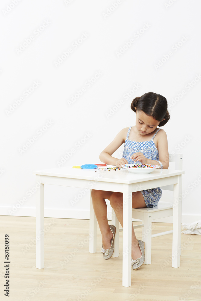 Young girl at table playing with beads Young girl at table playing with beads