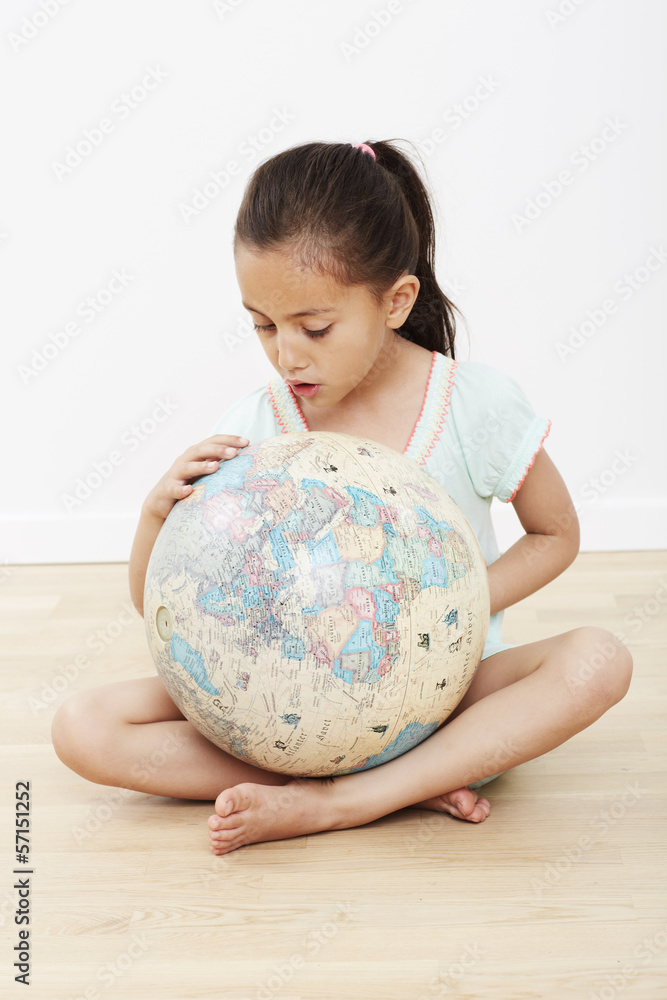 Young girl sitting on floor with globe Young girl sitting on floor with globe