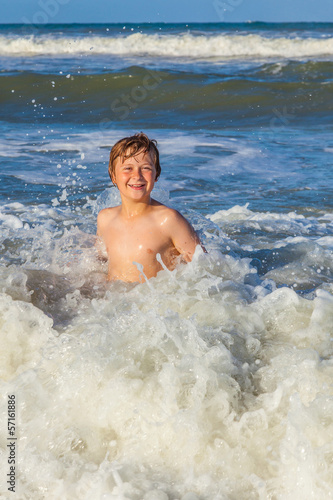 young boy enjoys the waves of the blue sea © travelview