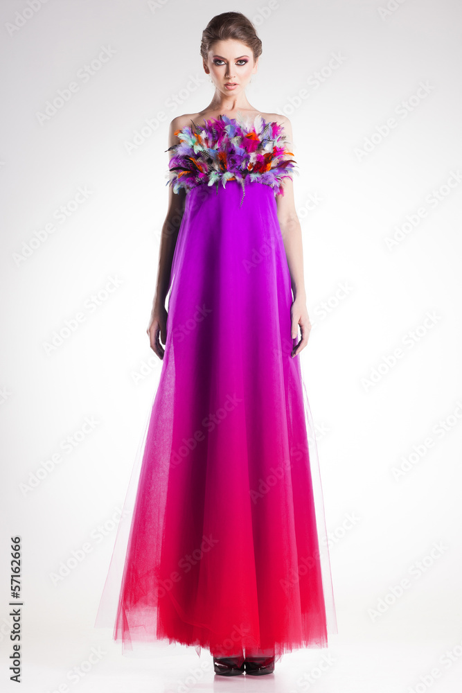 beautiful woman model in long colorful dress with feathers