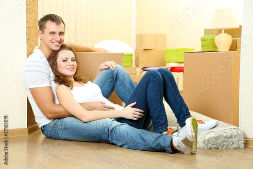 Young couple with boxes in new home on room background © Africa Studio