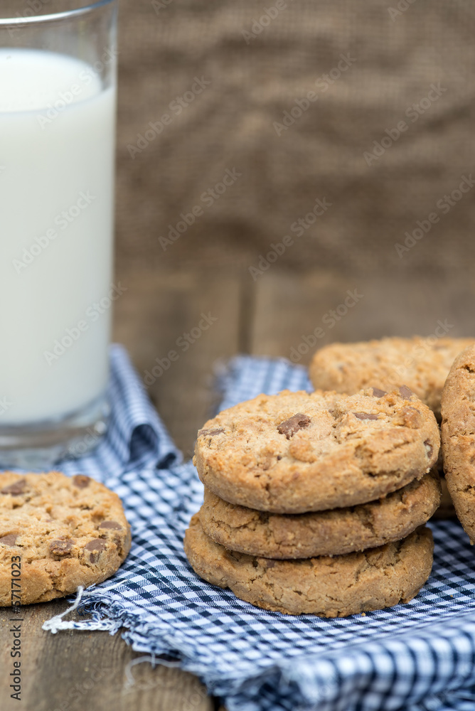 Rustic setting with chocolate chip cookies and glass of milk Rustic setting with chocolate chip cookies and glass of milk