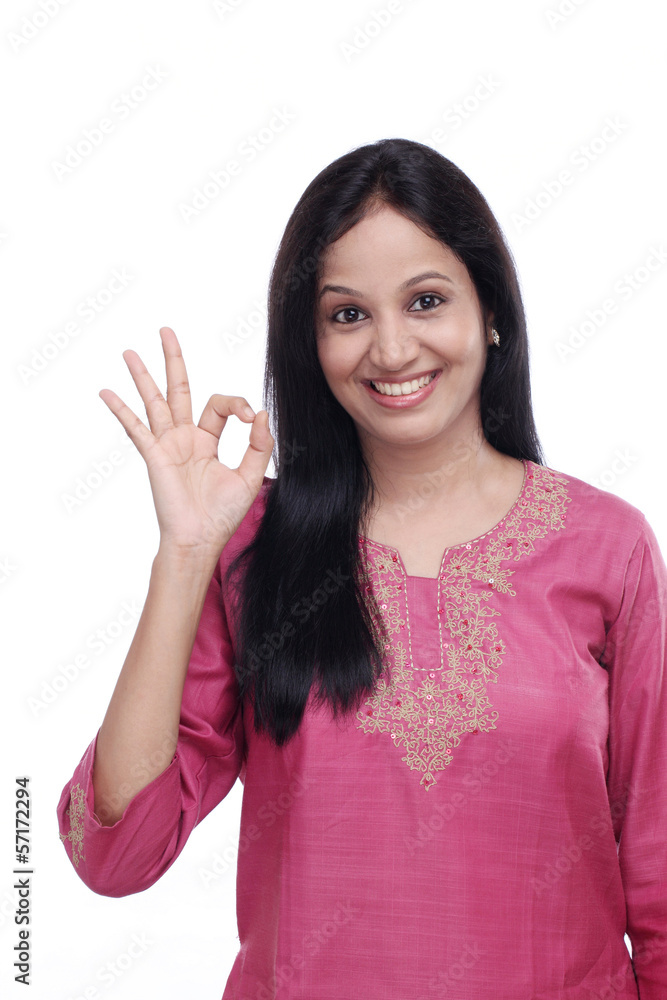 Young indian girl showing OK sign against white Young indian girl showing OK sign against white