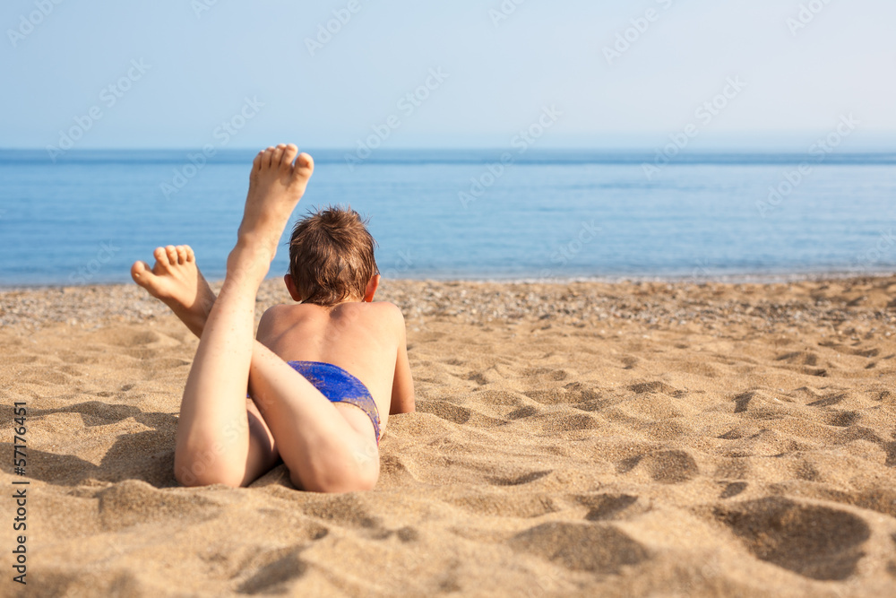 Happy boy lying on the beach