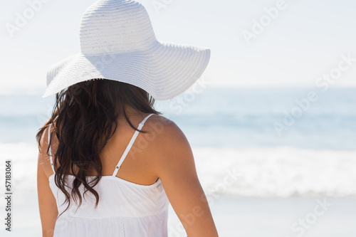 Pretty brunette in white sunhat looking at the ocean