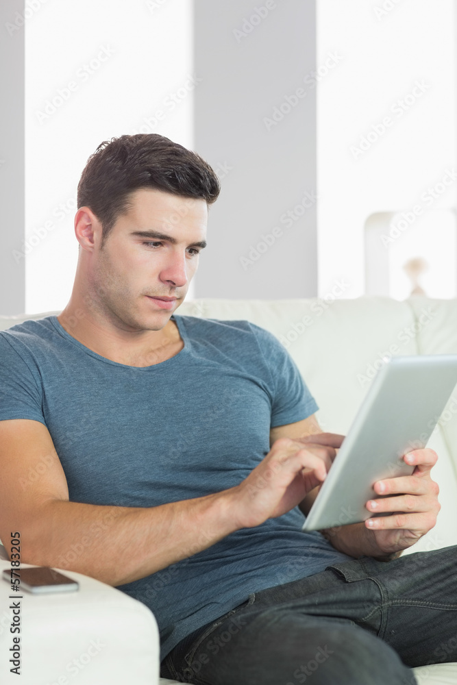 Peaceful handsome man relaxing on couch using tablet Peaceful handsome man relaxing on couch using tablet