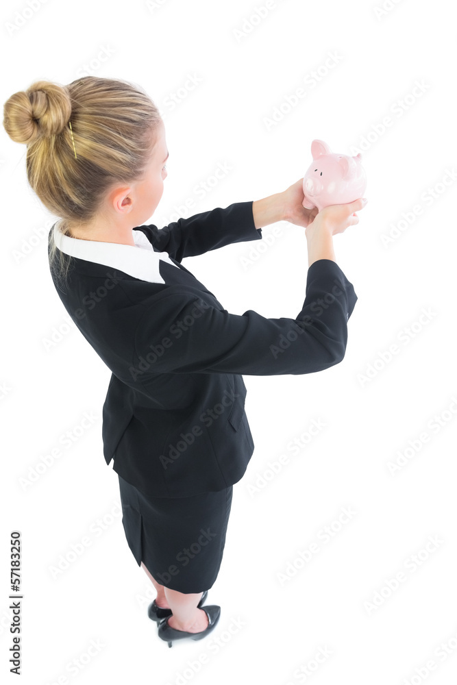 Blonde young businesswoman holding a piggy bank Blonde young businesswoman holding a piggy bank