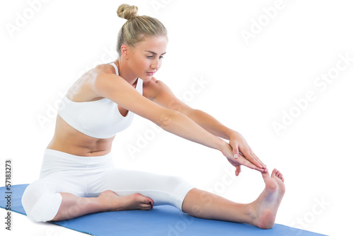Toned focused blonde sitting on exercise mat stretching right le