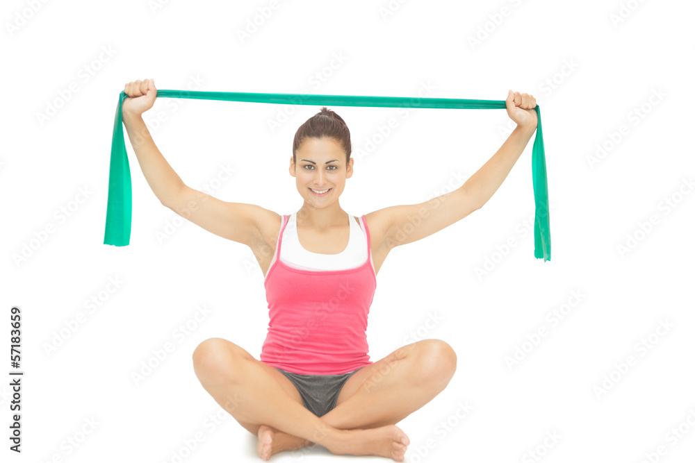 Naklejka premium Pretty sporty brunette stretching with resistance band sitting c