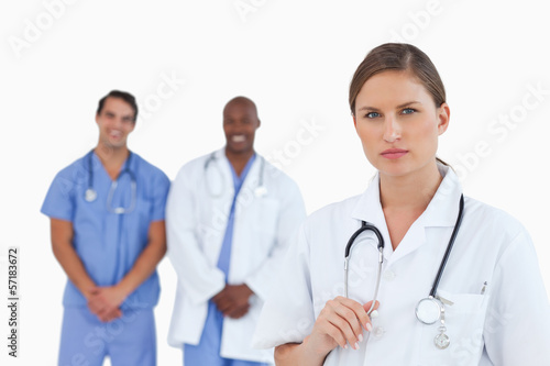 Serious looking female doctor with male colleagues behind her
