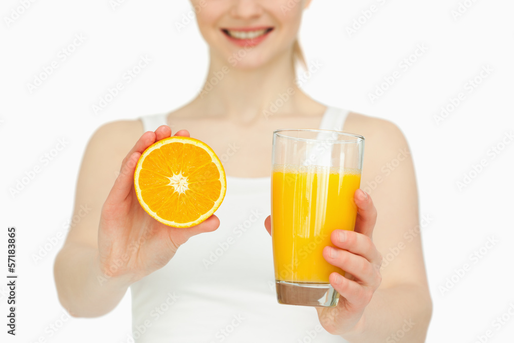 Woman presenting an orange while holding a glass Woman presenting an orange while holding a glass