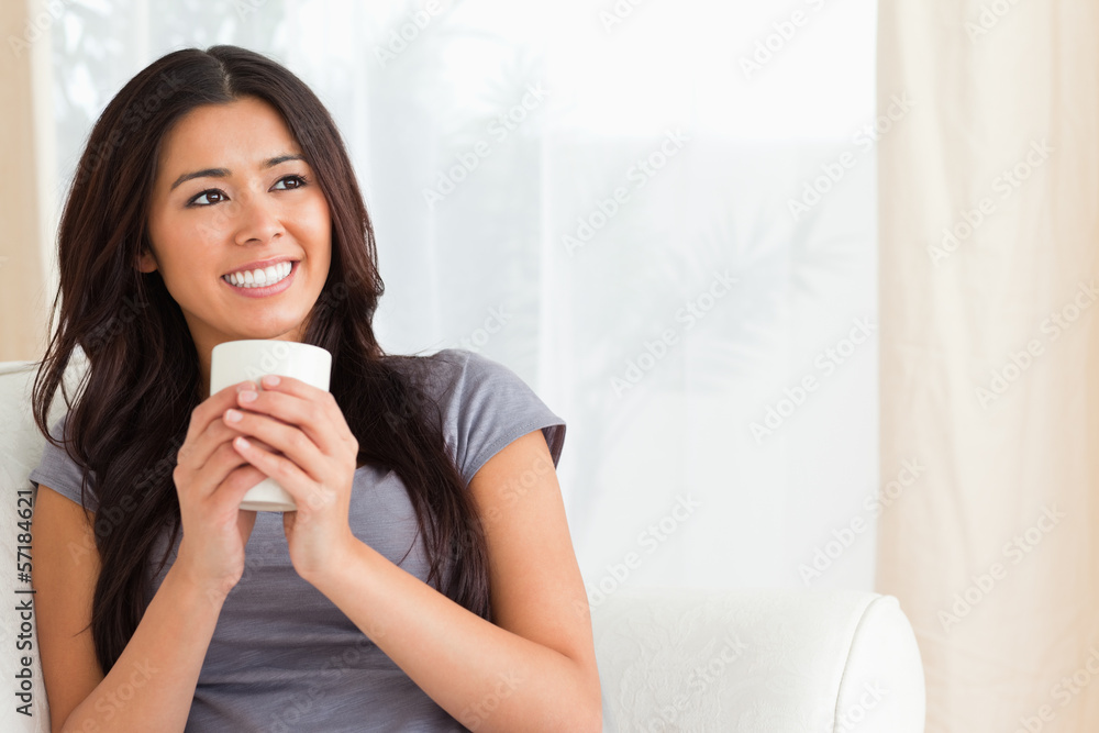 smiling woman holding a cup looking at the ceiling smiling woman holding a cup looking at the ceiling
