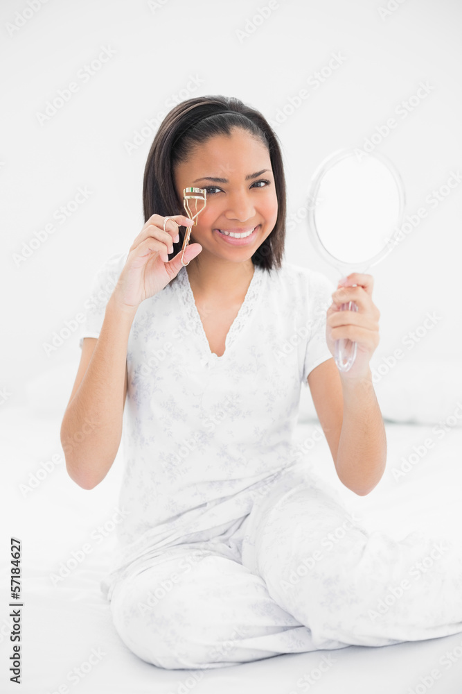 Happy young dark haired model using eyelash curler Happy young dark haired model using eyelash curler