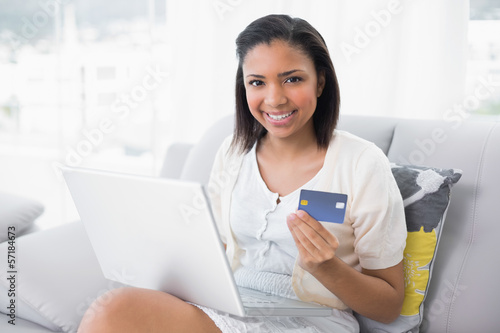 Pleased young dark haired woman in white clothes shopping online