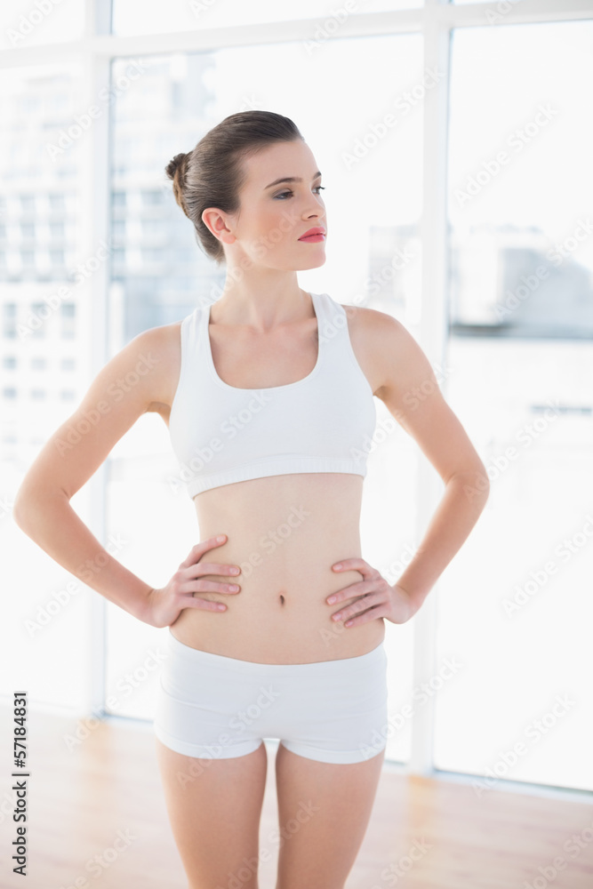 Unsmiling fit brown haired model in sportswear posing with hands