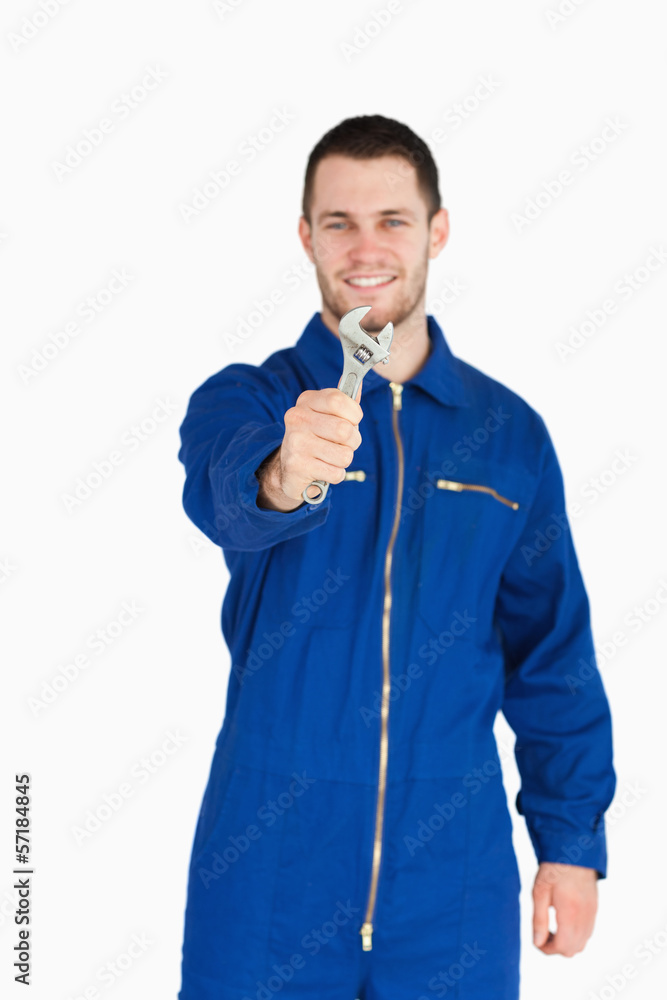 Wrench shown by smiling young mechanic in boiler suit Wrench shown by smiling young mechanic in boiler suit