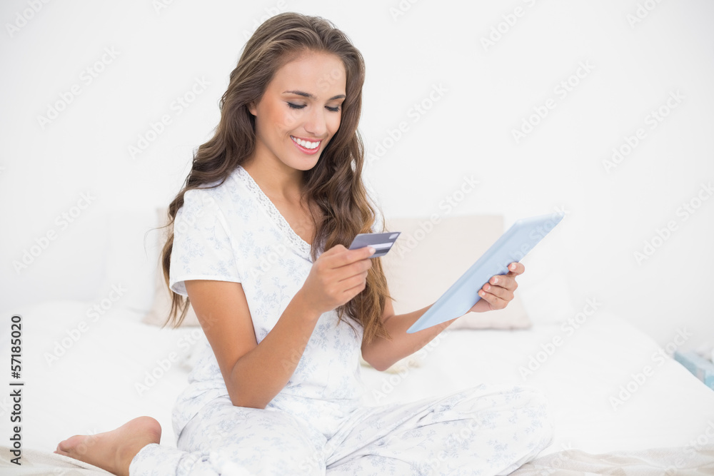Smiling attractive brunette holding credit card and tablet Smiling attractive brunette holding credit card and tablet