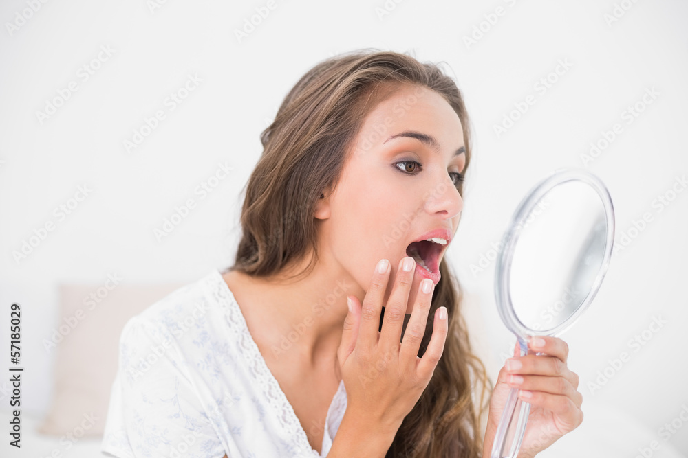 Attractive brunette opening mouth and looking at mirror Attractive brunette opening mouth and looking at mirror