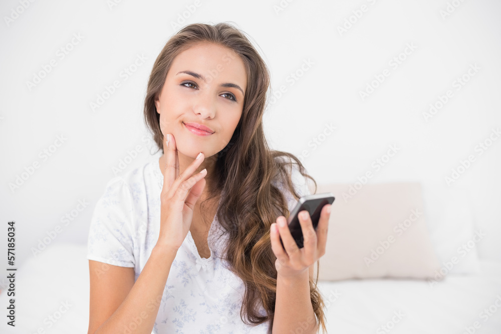 Thoughtful smiling brunette holding smartphone Thoughtful smiling brunette holding smartphone