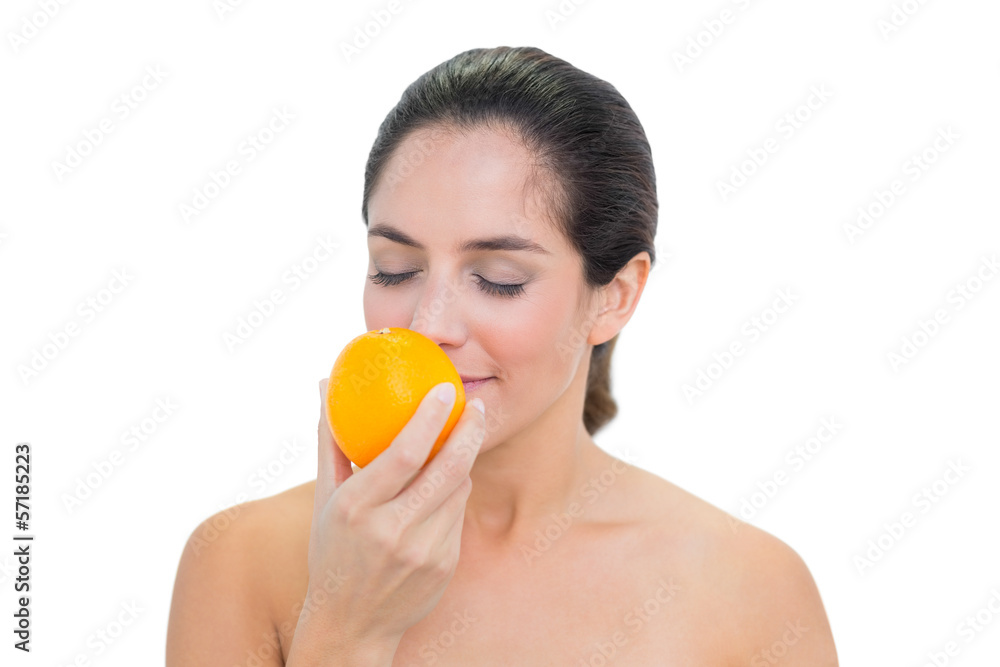 Smiling bare brunette smelling an orange Smiling bare brunette smelling an orange