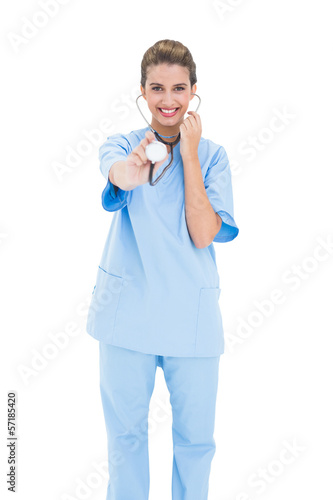 Amused brown haired nurse in blue scrubs playing with her stetho photo