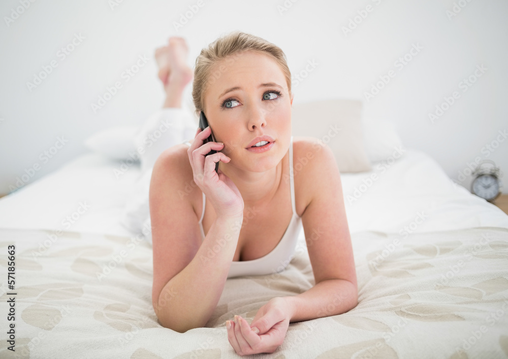 Natural skeptic blonde lying on bed and using smartphone Natural skeptic blonde lying on bed and using smartphone