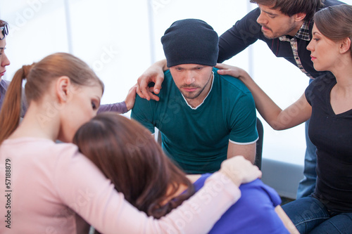Valokuva Several people comforting young man on background.