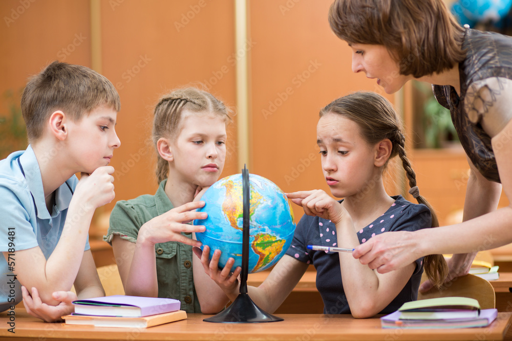 school kids studying a globe together with teacher school kids studying a globe together with teacher