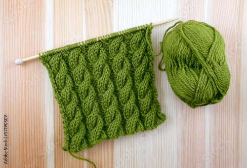 Green cable stitch knitting with a ball of yarn