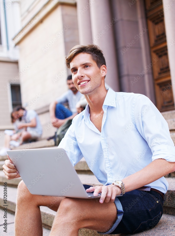 Handsome young man with laptop sitting on a steps outdoors