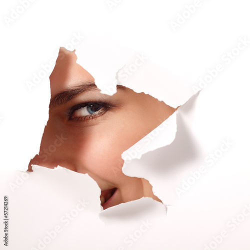 Fotografie cheerful teen girl peeping surprised through hole of paper
