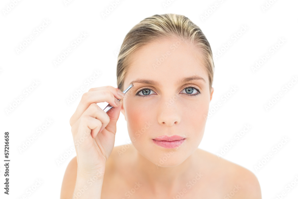 Focused fresh blonde woman plucking her eyebrows