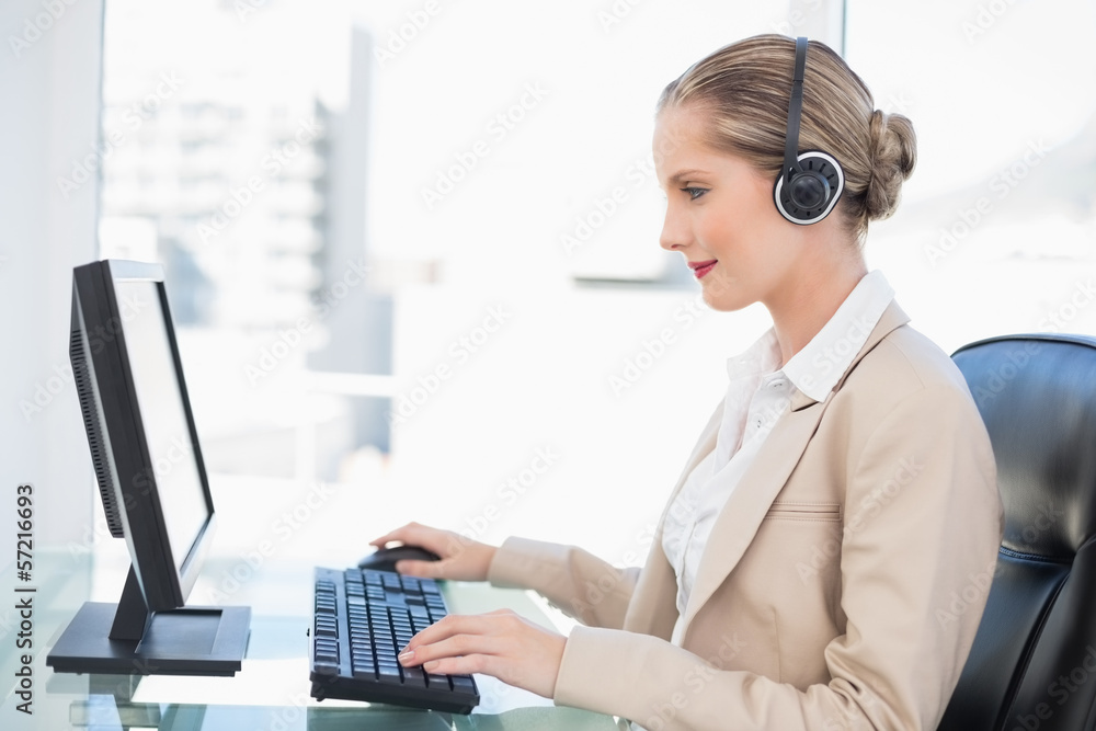 Smiling blonde call centre agent working on computer Smiling blonde call centre agent working on computer