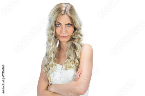 Doubtful model in white dress rising her eyebrow